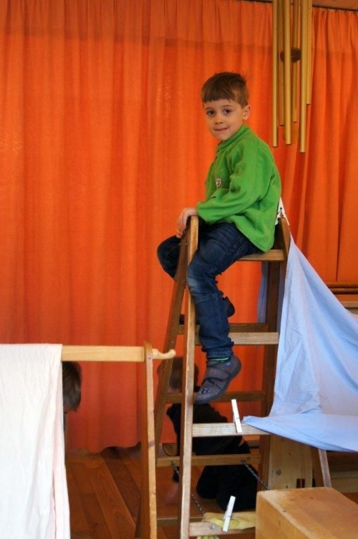 Kind klettert im Gruppenraum der Spielgruppe auf ein Holzgerüst