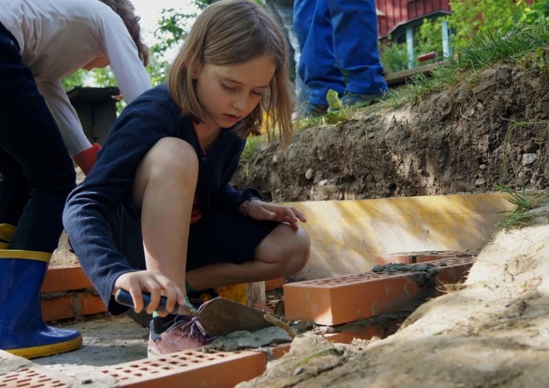 Schülerinnen und Schüler mauern in der Hausbauepoche eine Wand auf